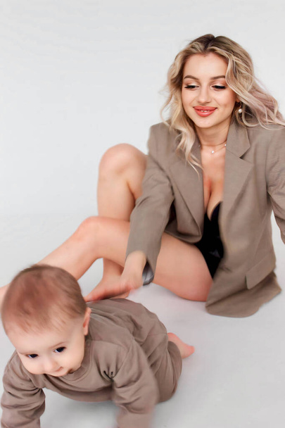 Linda mãe loira sexy em uma jaqueta bege e com um filho bebê - Foto, Imagem