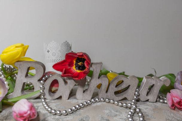 Auf Französisch geschriebenes Wort Glück (bonheur is Happiness) in Holz geschnitzt, umgeben von Tulpen und einer Kette aus grauen Perlen auf einem Hocker im Boudoir von Madame - Foto, Bild