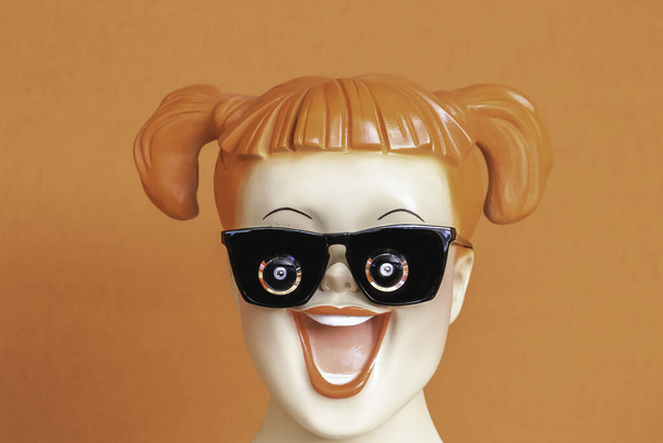 Gesicht des lächelnden rothaarigen Teenie-Models auf orangefarbenem Hintergrund mit in Bettdecke gebundenen Haaren, Brille mit integrierter Kamera - neue Technologie - Foto, Bild