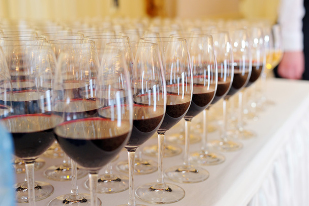 Verres de vin rouge en rangée sur une table
 - Photo, image