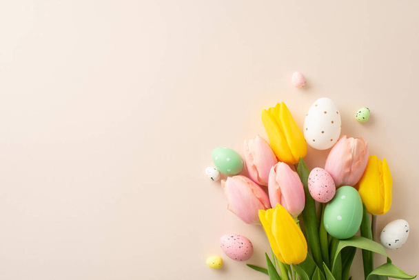 Celebre a Páscoa com esta deliciosa imagem de vista superior exibindo um encantador buquê adornado com ovos coloridos e tulipas frescas. O fundo bege pastel cria uma configuração serena para sua mensagem - Foto, Imagem