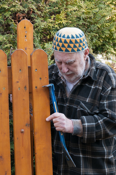 Vanha mies korjaamassa porttia
 - Valokuva, kuva