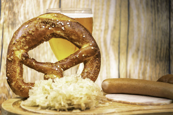 Oktober Fest avec un verre de bière un bretzel géant et une choucroute garnie sur une assiette en bois - Photo, image