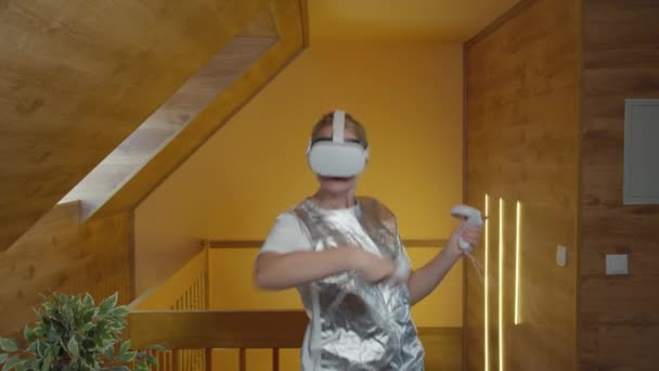 Modern bir evde sanal gerçeklik kulaklığı kullanan günlük giysili beyaz bir kadın. - Video, Çekim