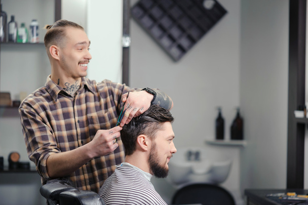 Barber cuts hair of a man - 写真・画像