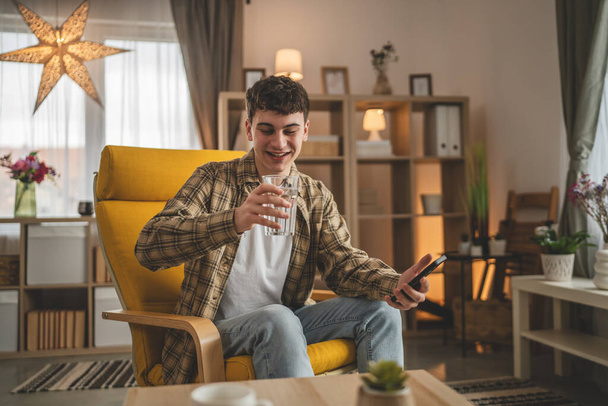 portret van man jong Kaukasisch man tiener hold glas water thuis - Foto, afbeelding