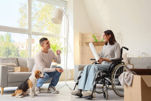 Mladý muž a jeho žena na invalidním vozíku s bígl pes ovinutí lampa na pohyblivý den - Fotografie, Obrázek