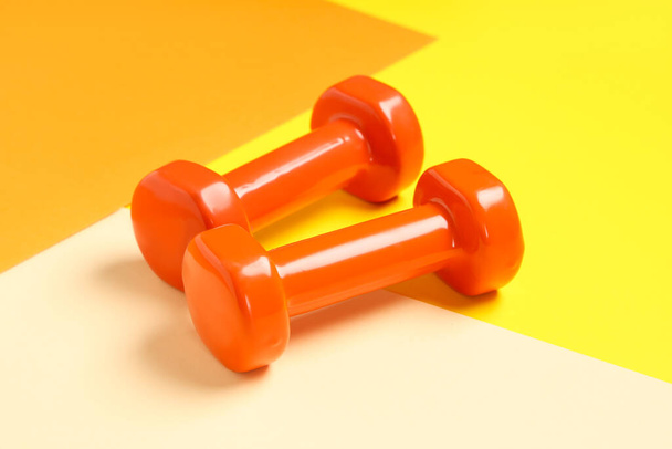Orange dumbbells on color background - Photo, Image
