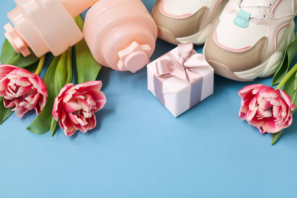 Dumbbells, shoes, gift and tulip flowers for International Women's Day on color background - Photo, Image