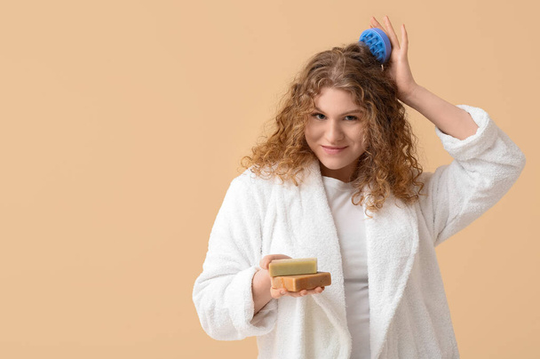 Belle jeune femme avec masseur du cuir chevelu et barres de shampooing sur fond beige - Photo, image