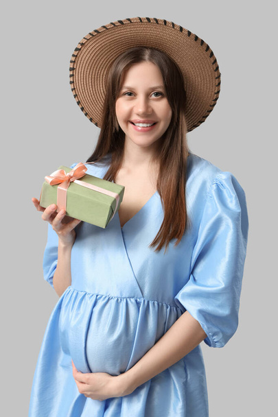 Gri arka planda hediye kutusu olan güzel hamile bir kadın. Uluslararası Kadınlar Günü - Fotoğraf, Görsel
