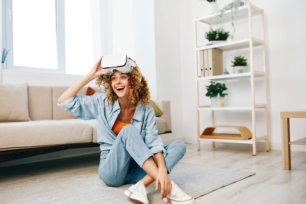 Virtual Reality Delight : Une jeune femme souriante de joie, utilisant des lunettes VR dans un salon intérieur moderne - Photo, image