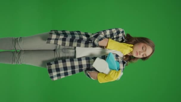 Vertikální pohled.Zelená obrazovka.Portrét přemýšlivé mladé ženy ve žluté ochranné gumové rukavice drží čisticí sprej láhev a hadr v ruce.Home Office Organization Tips. - Záběry, video
