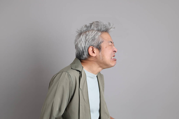 Der asiatische Mann der 40er Jahre mit schicker Freizeitkleidung steht auf dem grauen Hintergrund.  - Foto, Bild