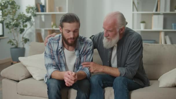 Głęboka rozmowa między pokoleniami młodych mężczyzn i starszych na kanapie omawiać życie, wymiana doświadczeń, serdeczna komunikacja, wsparcie emocjonalne, zrozumienie różnic mentoring, wartości rodzinne - Materiał filmowy, wideo
