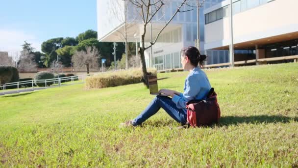 Egy egyetemi hallgató az egyetemen a laptopjával felkarolja a kültéri nyugalmat, magabiztos az e-learning utazásában.. - Felvétel, videó