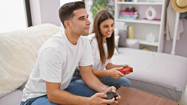 Mężczyzna i kobieta grają razem w gry wideo w przytulnym salonie, dając przykład spędzania wolnego czasu i nawiązywania więzi w domu. - Zdjęcie, obraz