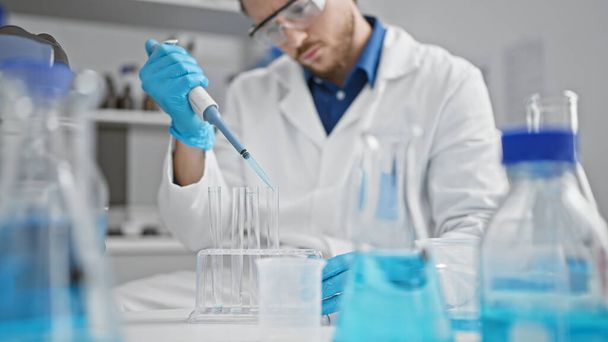Młody latynoski naukowiec wylewający płyn na probówkę w laboratorium - Zdjęcie, obraz