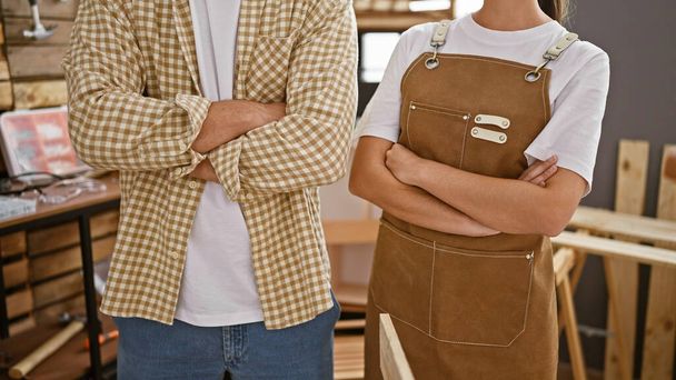 Homme et femme confiants avec les bras croisés dans un atelier de menuiserie créative portant des vêtements décontractés. - Photo, image