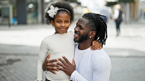 Αφροαμερικάνος πατέρας και κόρη χαμογελούν με αυτοπεποίθηση αγκαλιάζοντας ο ένας τον άλλον στο δρόμο - Φωτογραφία, εικόνα