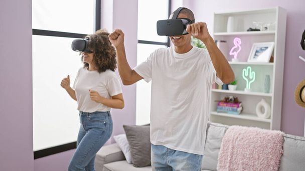 Λάμψη παιχνιδιών, η αγάπη του όμορφου ζευγαριού ανθίζει σε βιντεοπαιχνίδι χορού εικονικής πραγματικότητας απολαμβάνοντας τη μουσική, χρησιμοποιώντας φουτουριστικά gadget γυαλιά στο σπίτι - Φωτογραφία, εικόνα
