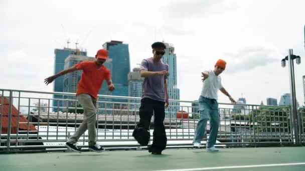 Eine Gruppe erfahrener Breakdancer führt gemeinsam Hip-Hop-Schritte auf dem Dach mit Blick auf die Stadt oder den Wolkenkratzer vor. Hübsches Hipster-Team zieht zu flippiger Musik auf öffentlichen Plätzen um. Outdoor-Sport 2024. Schwungvoll. - Filmmaterial, Video