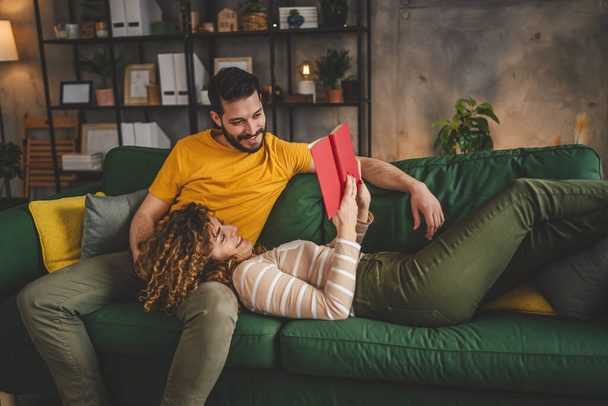 mężczyzna i kobieta biały dorosłych para czytać książki w domu na kanapie - Zdjęcie, obraz