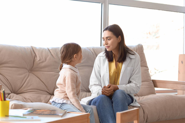 Kobieta psycholog z małą dziewczynką siedzi na kanapie w biurze - Zdjęcie, obraz