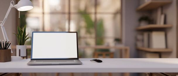 Une table blanche avec un ordinateur portable à écran blanc et un décor est présente dans une pièce de bureau moderne et confortable. 3d rendu, illustration 3d - Photo, image
