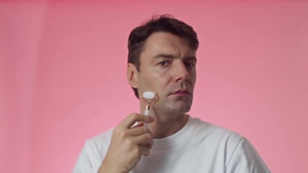 Medium schot van middelbare leeftijd man van Kaukasische etniciteit met behulp van roller tijdens het doen van gezichtsmassage - Video