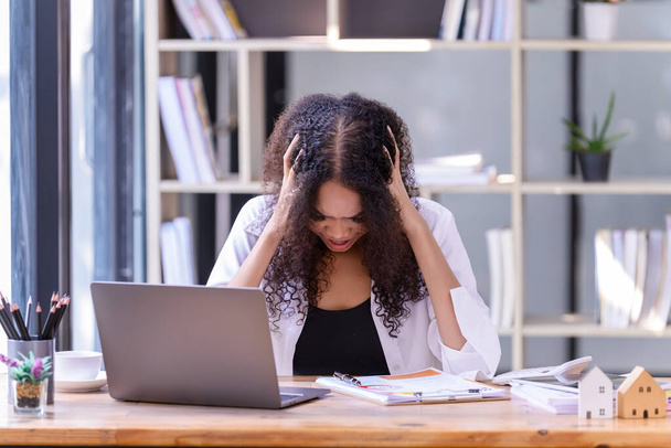 Las mujeres de negocios están estresadas con el trabajo delante de una computadora portátil y documentos en papel en la oficina. Concepto empresarial. - Foto, imagen