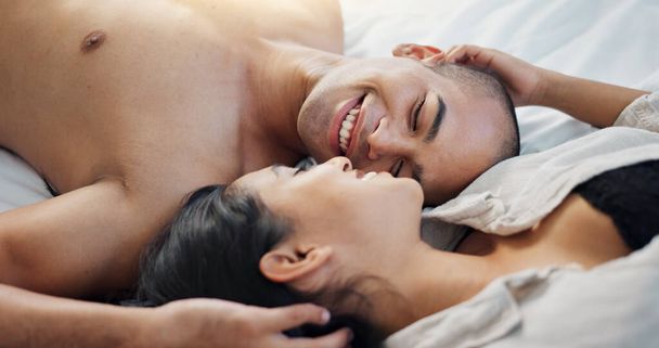 Gelukkig stel, pratend in bed met liefde, intimiteit en romantiek thuis voor relatie, seks en hechting. Jongeren, vrouw en man ontspannen in de slaapkamer met zachte aanraking en kus voor Valentijnsdag. - Foto, afbeelding