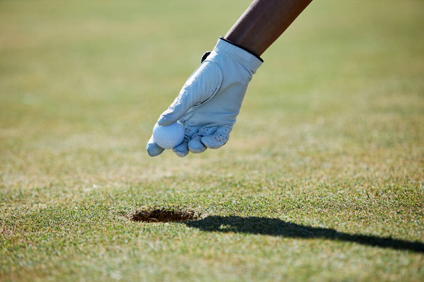 Fechar a mão enluvada pegando bola de golfe do buraco, espaço cópia - Foto, Imagem