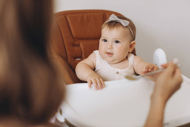Madre che nutre cibo sano alla sua adorabile figlioletta seduta sul seggiolone - Foto, immagini