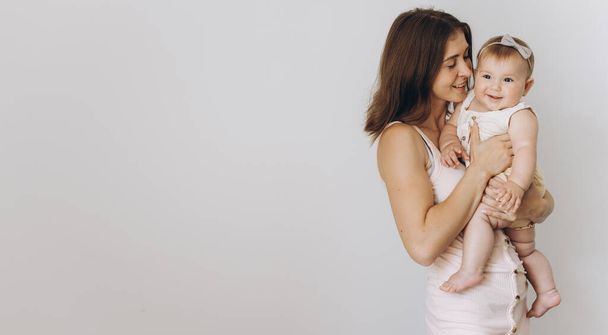 gelukkig jong moeder met haar schattig baby meisje op wit achtergrond - Foto, afbeelding
