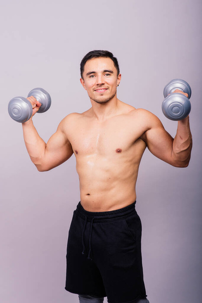 Shirtless bodybuilder showing his great body and holding dumbells. - Foto, Imagem