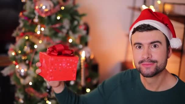 zbliżenie materiał z szczęśliwy przystojny młody człowiek z czerwony prezent pudełko świętowanie Boże Narodzenie  - Materiał filmowy, wideo