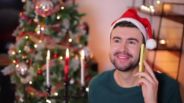 zbliżenie wideo szczęśliwy przystojny młody człowiek rozmawia przez telefon świętując Boże Narodzenie  - Materiał filmowy, wideo