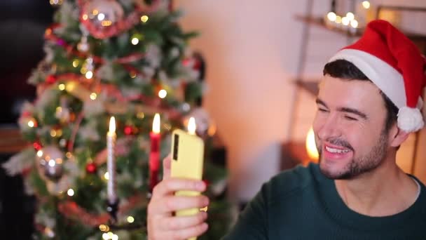 zbliżenie wideo szczęśliwy przystojny młody człowiek za pomocą smartfona świętowanie Boże Narodzenie  - Materiał filmowy, wideo