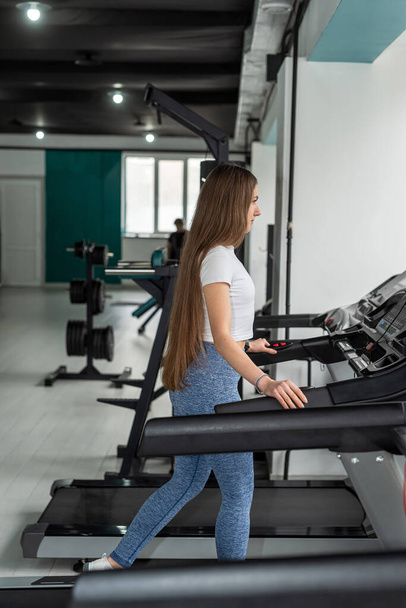 Portrait de jolie jeune femme prenant une pause de courir sur la machine de tapis roulant à la salle de gym. Fitness gym pour un mode de vie sain - Photo, image