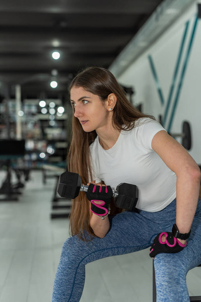 Young fitness female trainer doing exercise and lifting dumbbells weights gym. Healthy lifestyle - Photo, Image