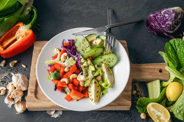Close-up, verse groentesalade op de keukentafel. Salade van paprika, kool en komkommer. Rauwe groentesalade, vegetarisch. - Foto, afbeelding