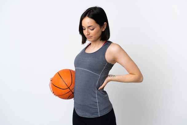 Mujer joven jugando baloncesto aislada sobre fondo blanco sufriendo de dolor de espalda por haber hecho un esfuerzo - Foto, Imagen