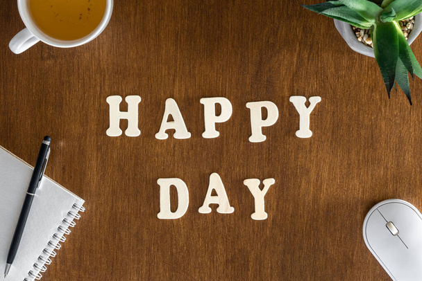 Η επιγραφή Happy Day, ξύλινα γράμματα στο τραπέζι του γραφείου, πάνω όψη. Επίπεδο φόντο γραφείου lay. - Φωτογραφία, εικόνα