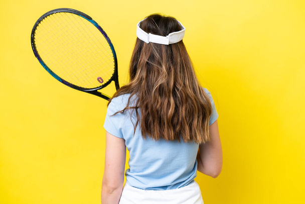 Nuori valkoihoinen nainen eristetty keltainen tausta pelaa tennistä - Valokuva, kuva