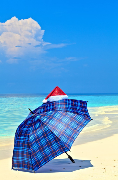 Ombrello blu è su una spiaggia con Babbo Natale
 - Foto, immagini