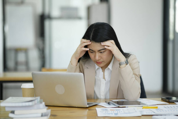 Οι εργαζόμενες γυναίκες είναι αγχωμένες και κουρασμένες. Κεφαλαλγία από τη σκέψη και την πίεση από την εργασία. - Φωτογραφία, εικόνα