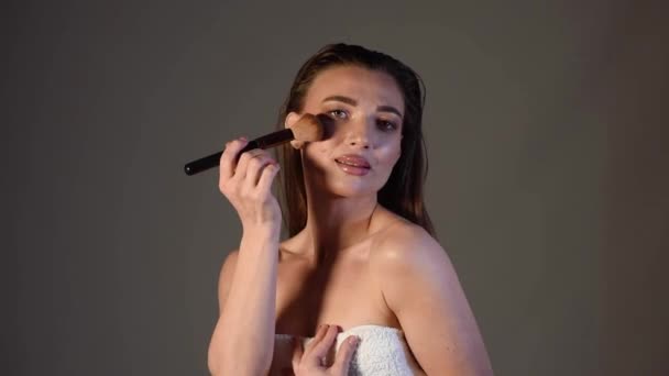 una joven se maquilla la cara con un cepillo. Imágenes FullHD de alta calidad - Metraje, vídeo