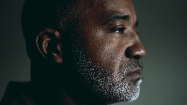 Pensive unshaven senior South American black man in deep thoughtful look during challenging times, feeling lost in quiet solitude introspecplation, close-up face - Кадры, видео