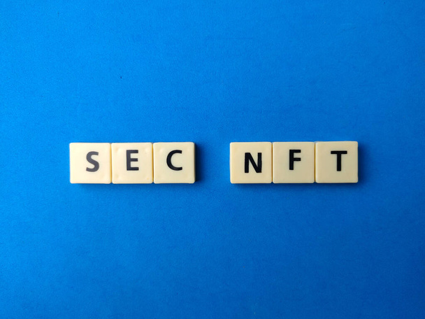 Вид сверху игрушки слово с текстом SEC NFT на синем фоне. - Фото, изображение